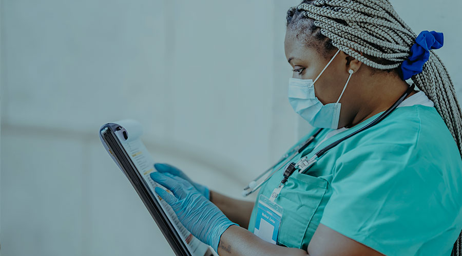 A Black female medical doctor checks a chart in a hospital setting