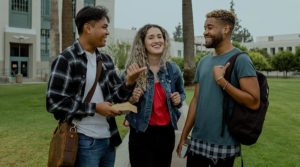 Three young professions, two men and a women of various ethnicities stand, talk and laugh