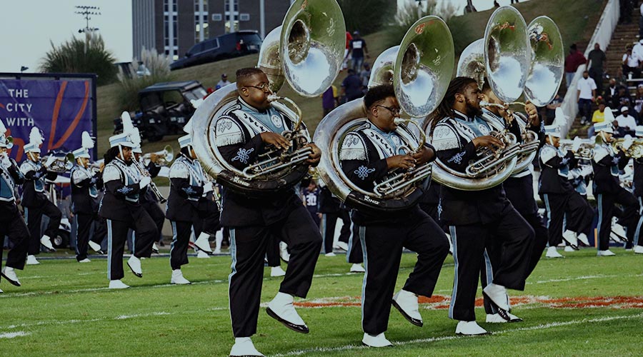 The low brass section of a Historically Black College or University marching band performs on a football field