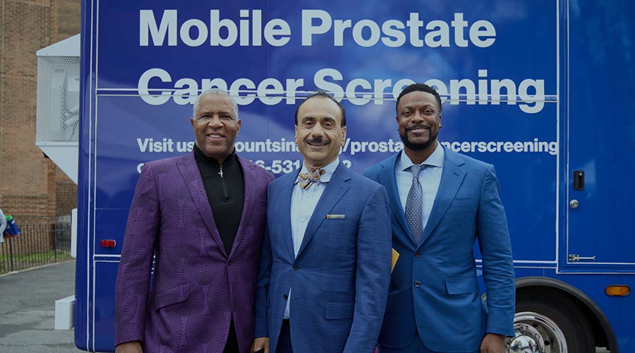 Robert F. Smith, Dr. Ash Tewari and Chris Tucker stand in front of the mobile prostate cancer screening unit