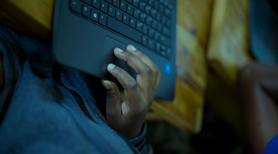 A Black man using a laptop that is sitting on a table.
