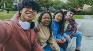 A photo of four young adults posing for a photo outside.