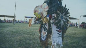 A photo of an indigenious peoples outside with native wear.