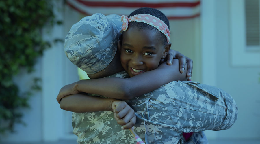 An image of a young Black girl as she hugs a Black veteran in a military uniform.
