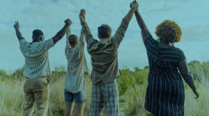 A group of people stand outside with their hands together, raised up in the air in unity.