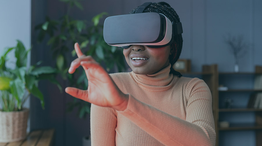 Black woman in an orange turtleneck wearing a virtual reality headset.
