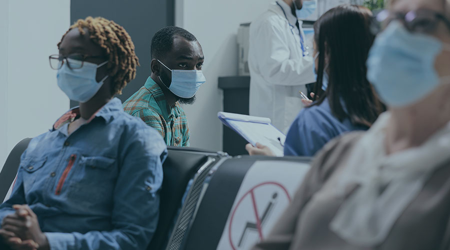 Image of a hospital setting with a doctor talking to an African American man and wearing a mask.