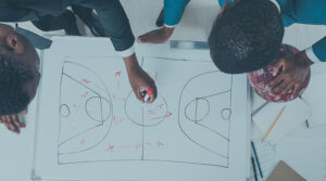 Image of two Black men in suits drawing a strategy down on a dry-erase board with a marker