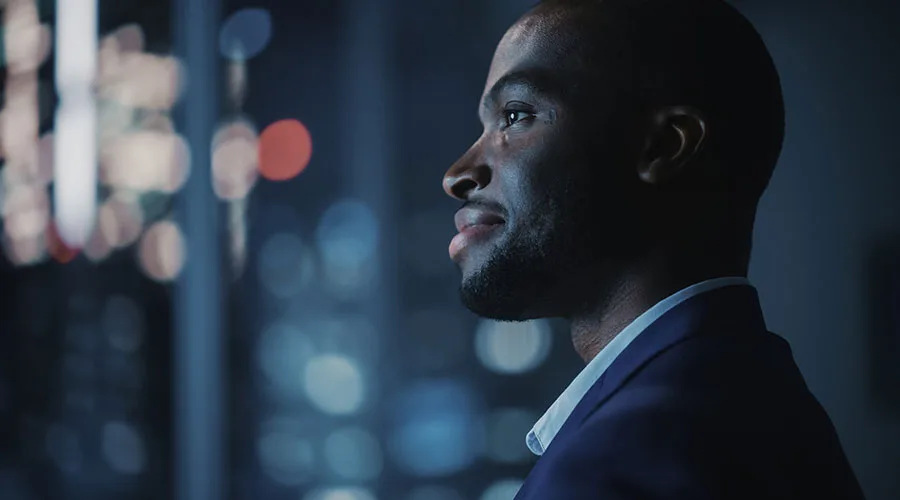 Young professional in a blue collared shirt and navy blue suit jacket looking into the distance