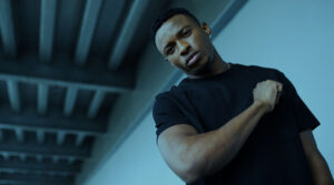 Image of a Black man in a black t-shirt with his fist to his chest