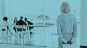 Woman in an office setting standing and facing a group of professionals sitting down