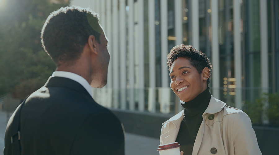 Image of a Black woman and man standing outside while dressed professionally