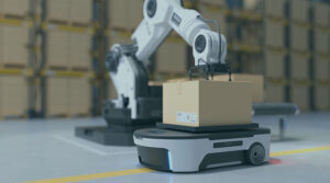 A robotic arm picks up a cardboard box off of another robotic machine in a storage facility