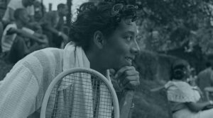 Tennis star Althea Gibson holds a tennis racket while looking into the distance