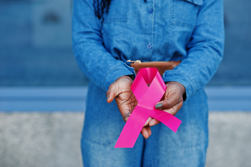 A woman wearing demin holding a breast cancer awareness sign in her hands