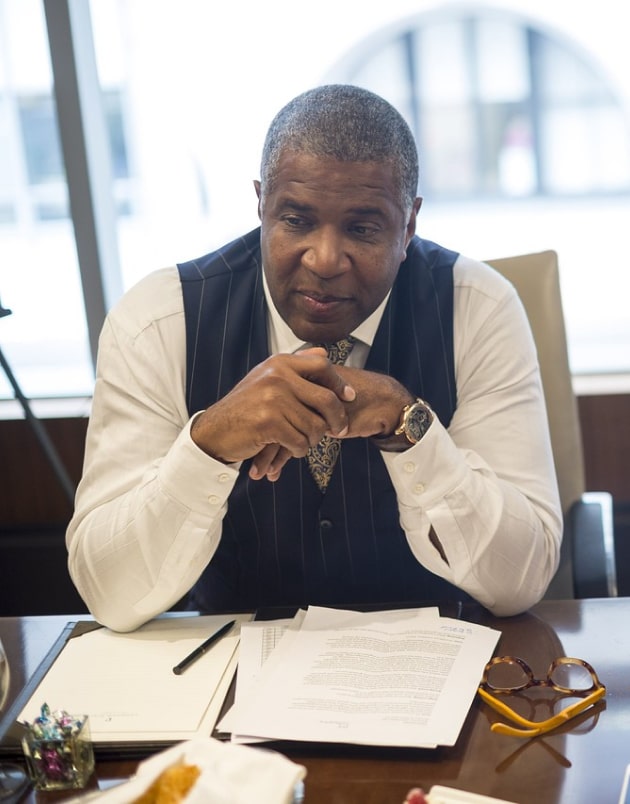 Robert F. Smith sits at a desk in an office with his hands crossed
