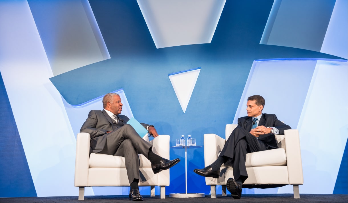 Robert F. Smith sits in a chair and speaks with interviewer with a Vista Equity Partners logo in the background