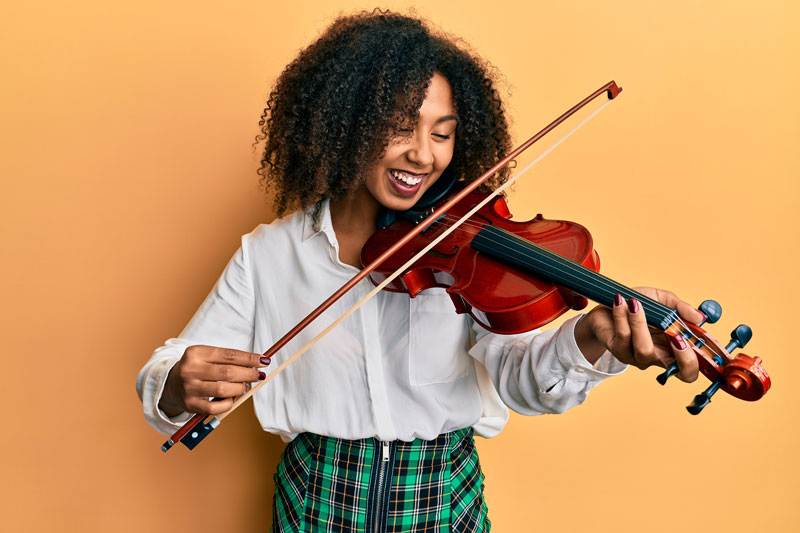 A woman smiles as she plays a violin