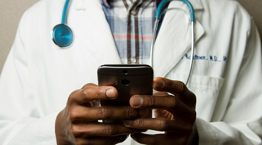 Closeup of a doctor in a white lab coat using a smartphone
