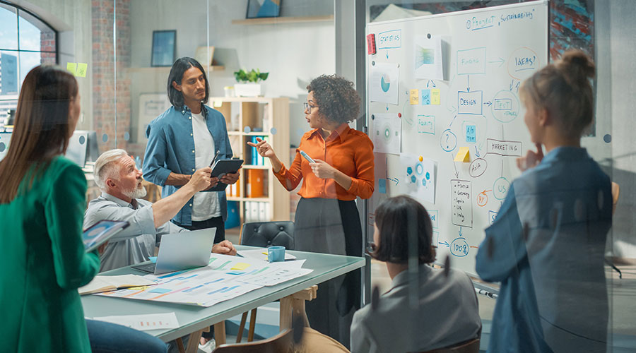 A diverse leadership team in a discussion in front of a whiteboard at the office.