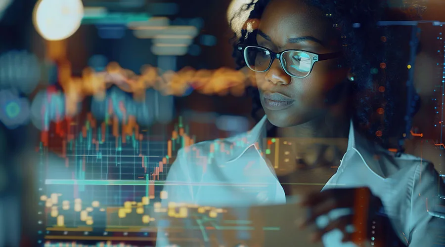 A woman in glasses and a collared shirt reviewing graphs and charts.