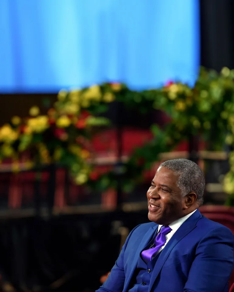 Robert F. Smith wears a blue suit as he sits in a chair smiling