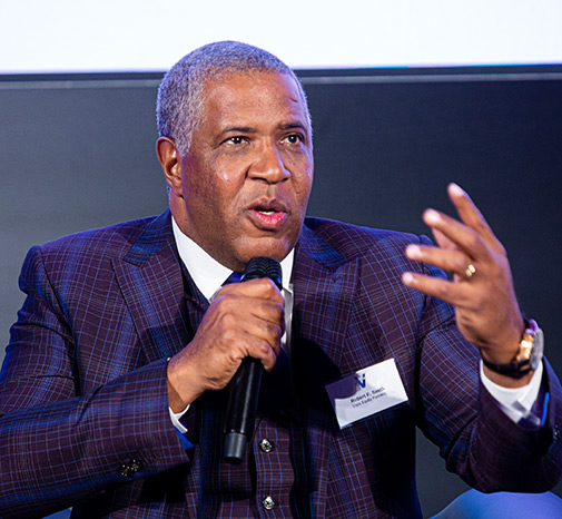 Robert F. Smith of Vista Equity Partners wears a suit and holds a microphone while he speaks