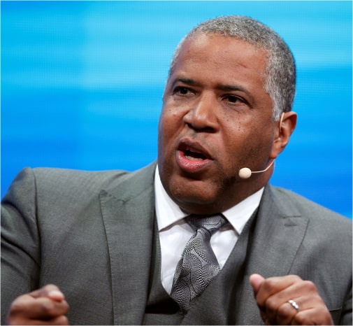 Robert F. Smith wears a headset and suit while speaking at an event