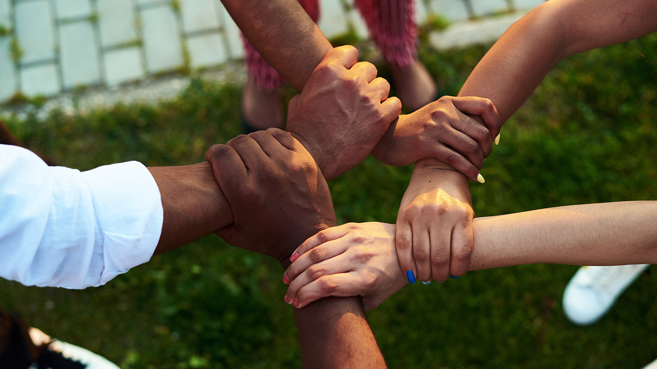 Five people bring their hands together to form a circle