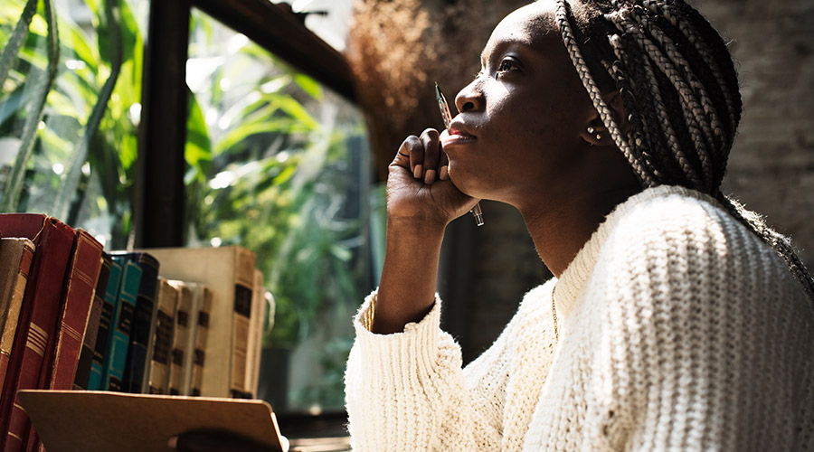 Woman in a white sweater at a desk in front of a window.